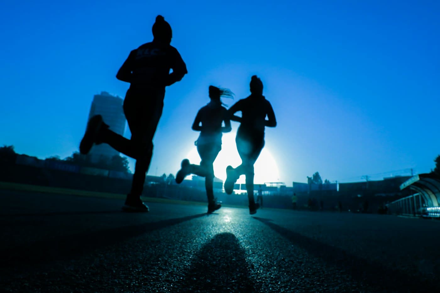 Three people running together at dusk